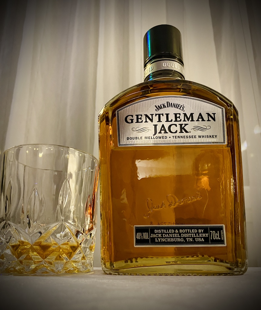 Flasche Jack Daniel’s Gentleman Jack mit Tumblerglas auf hellem Hintergrund