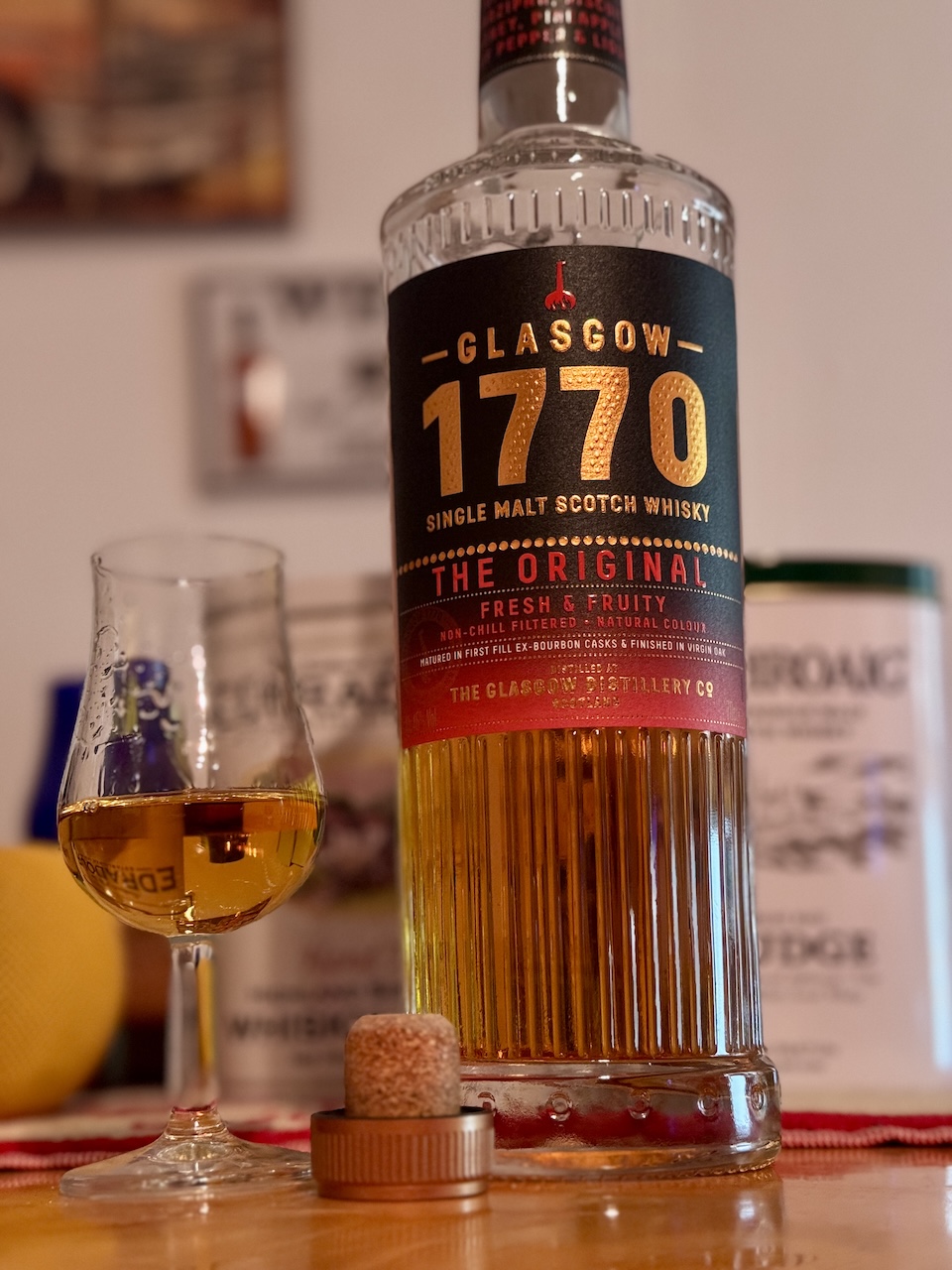 1770 Glasgow The Original Whiskyflasche mit Tasting-Glas auf Tisch, Hintergrund leicht unscharf.